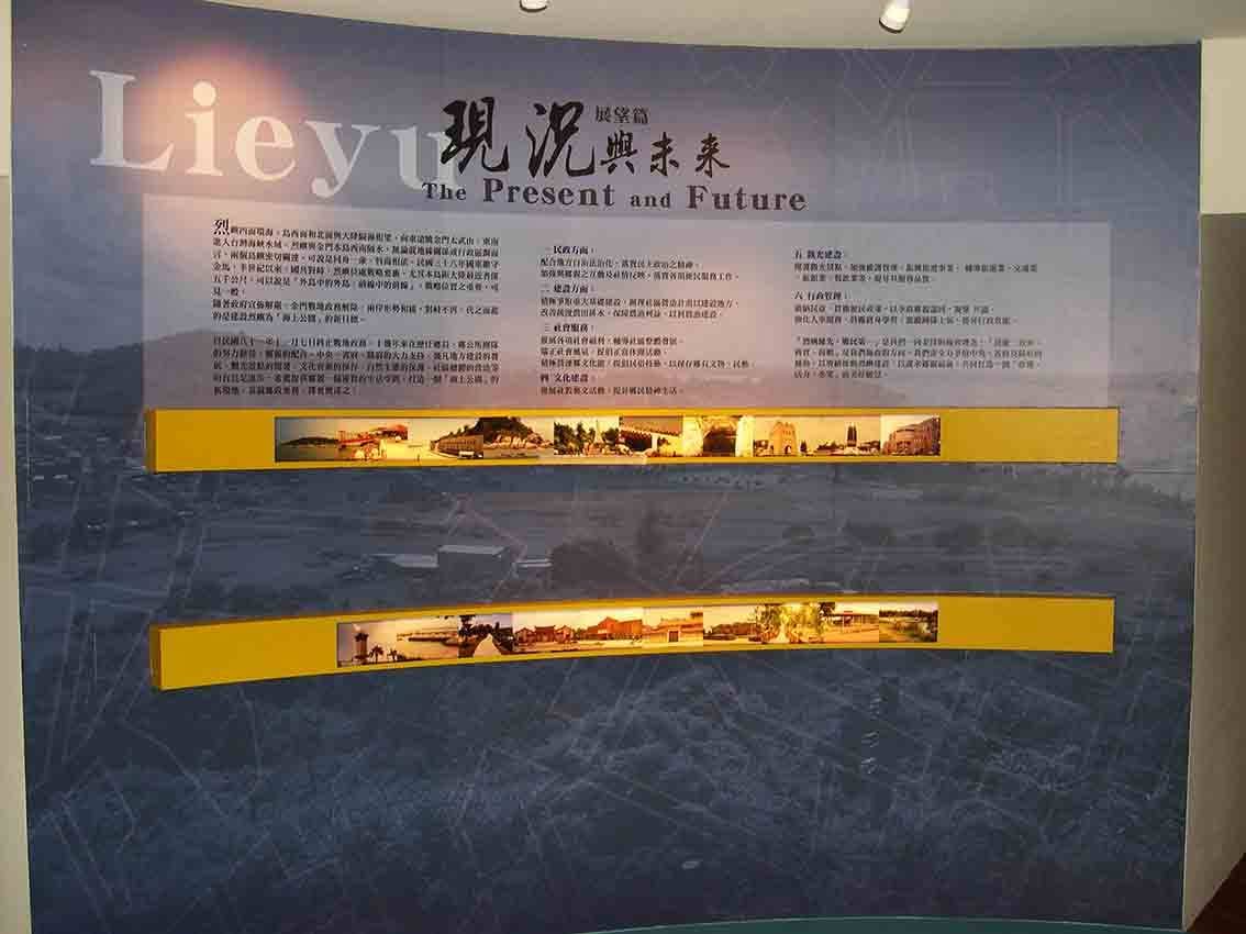 烈嶼鄉史館「現況與未來 The Present and Future」展區，深藍背板搭配兩道黃色長條燈箱影像帶
