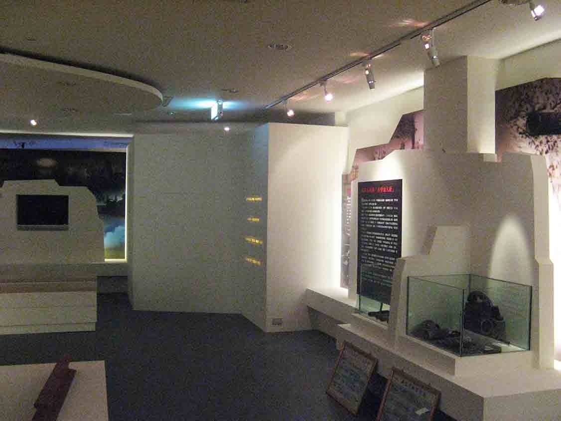 烈嶼鄉史館戰役展區白色量體與展示櫃，紅字標題大圖牆呈現戰地史料