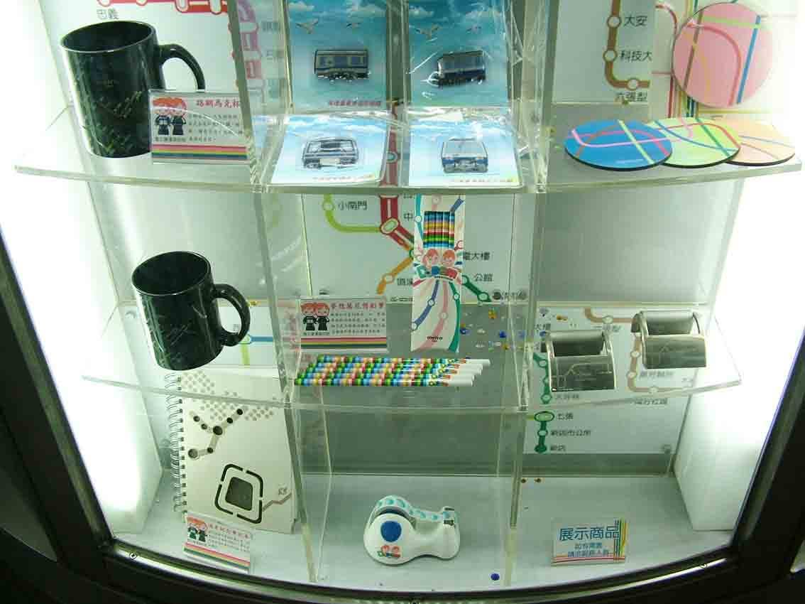 壓克力層板展示櫃特寫，馬克杯、彩色鉛筆與路網杯墊商品