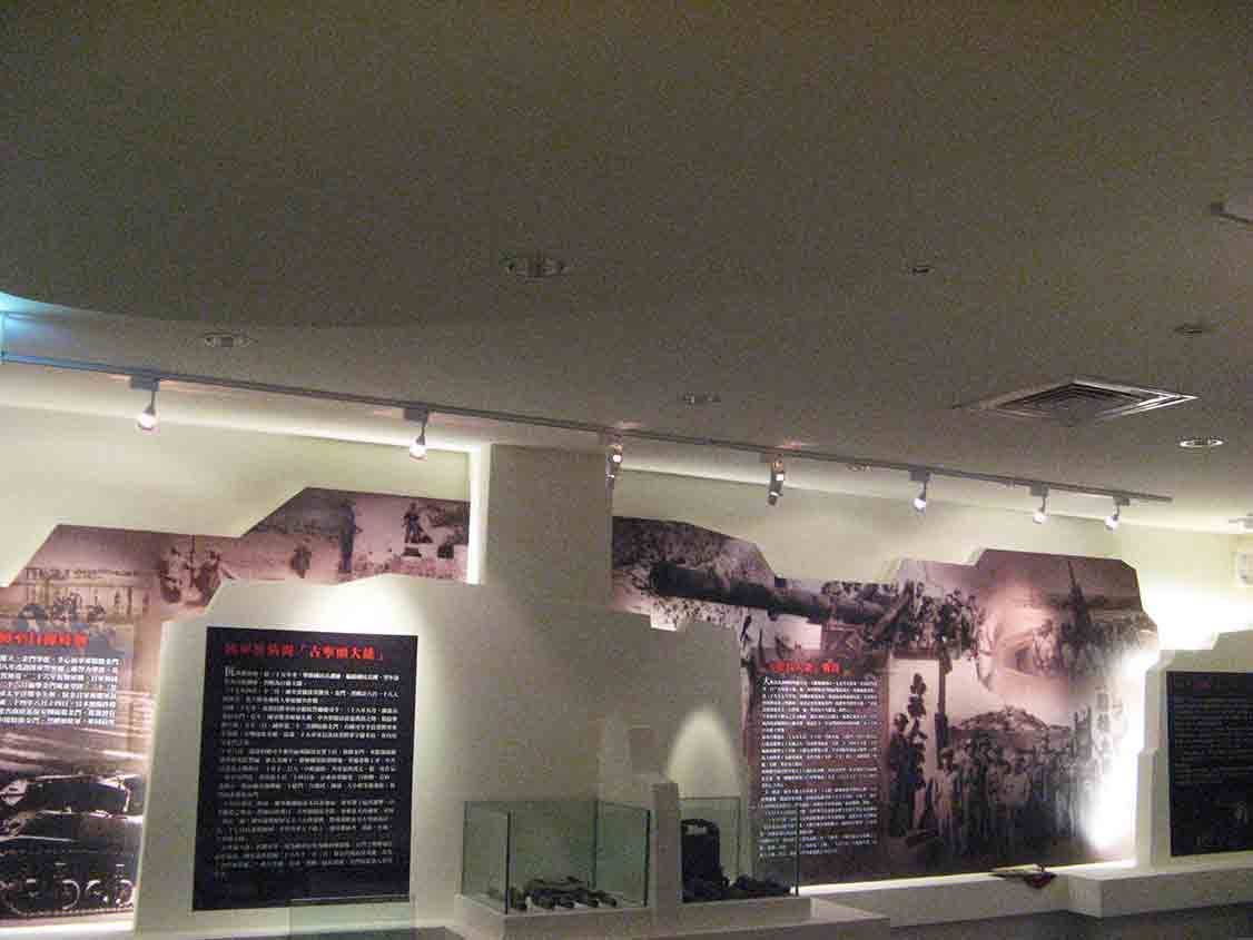 烈嶼鄉史館戰役全景大圖牆，碉堡造型輪廓裁切歷史影像，搭配天花軌道燈與展示櫃