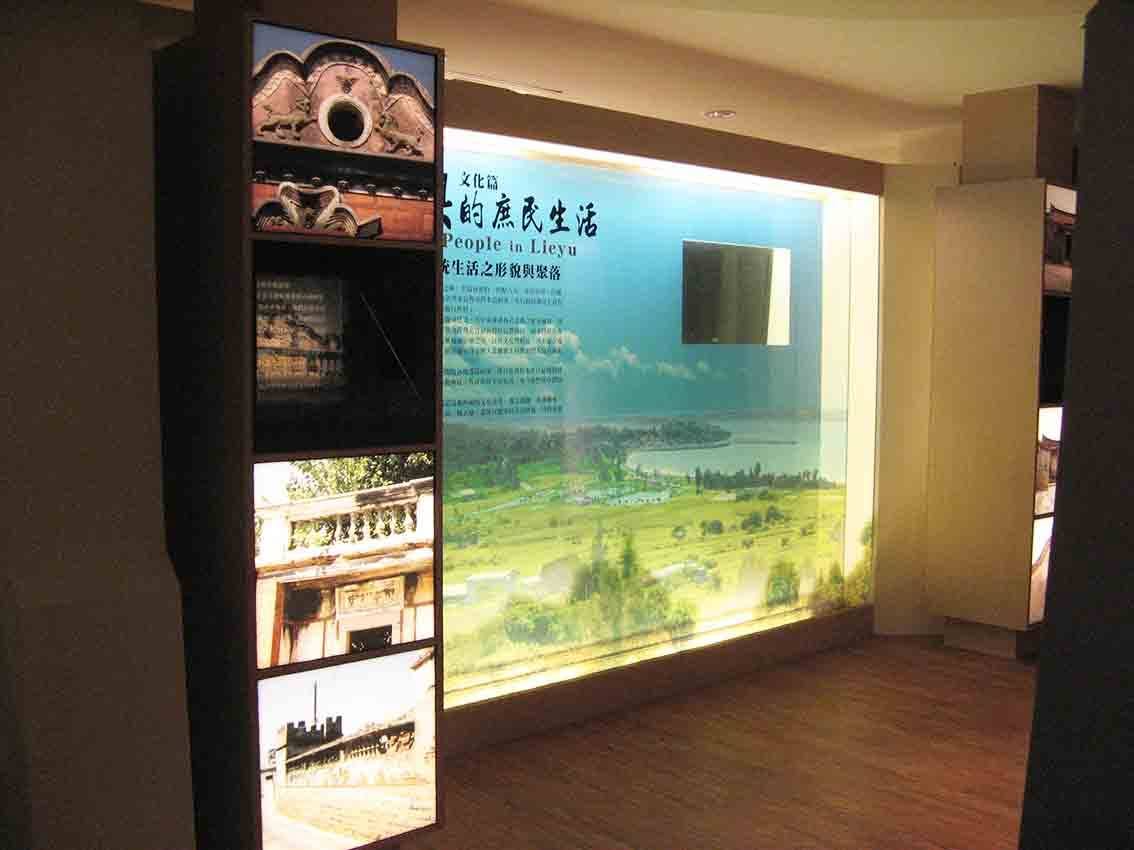 烈嶼鄉史館「烈嶼的庶民生活 Life of People in Lieyu」文化篇展區，大型空拍燈箱搭配側邊老建築剪影燈箱柱