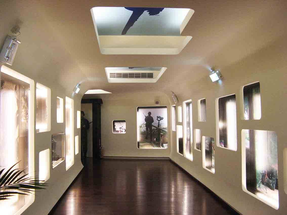 烈嶼鄉史館人物廊道展區，弧形拱頂走廊兩側鑲嵌發光圓角窗框，內嵌烈嶼軍民與聚落影像