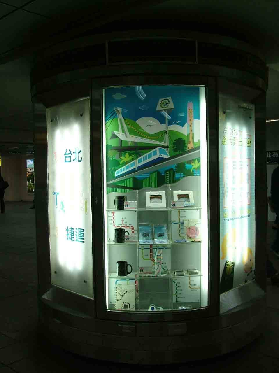 圓柱型燈箱展櫃整體視角，文湖線高架彩繪與商品陳列