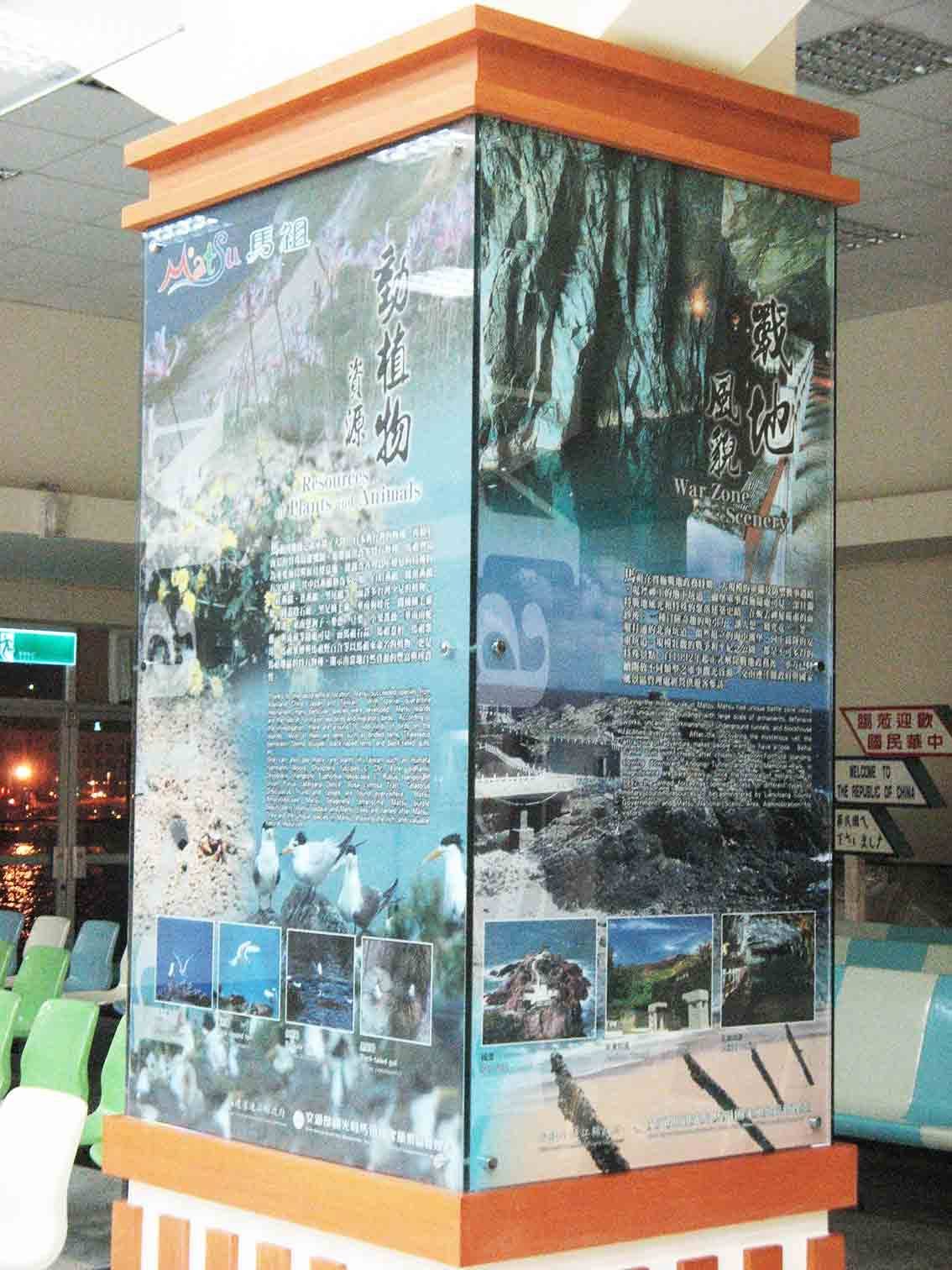 基隆碼頭候船室方柱包覆「馬祖 Matsu 動植物資源 / 戰地風貌 War Zone Scenery」大圖輸出，木製柱頭飾邊與下方候機座椅