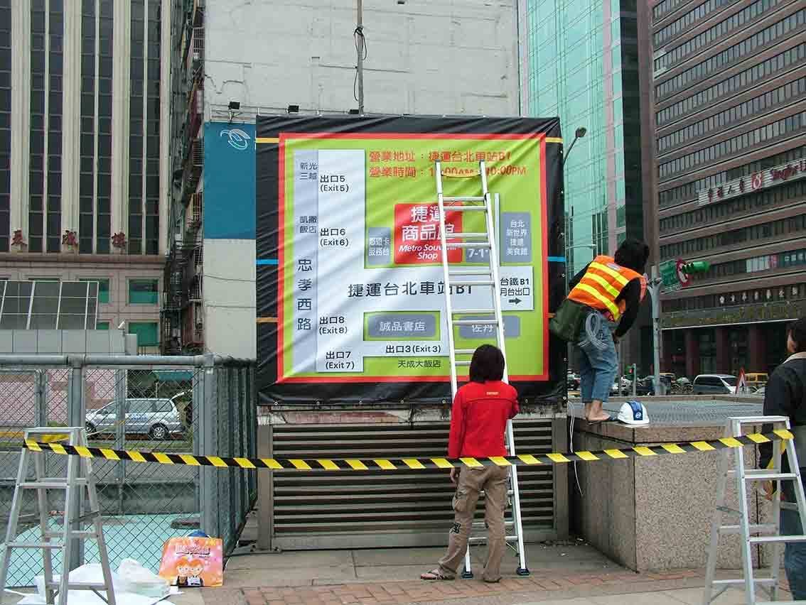 戶外大型路線指引帆布安裝現場，工作人員協力張掛大圖