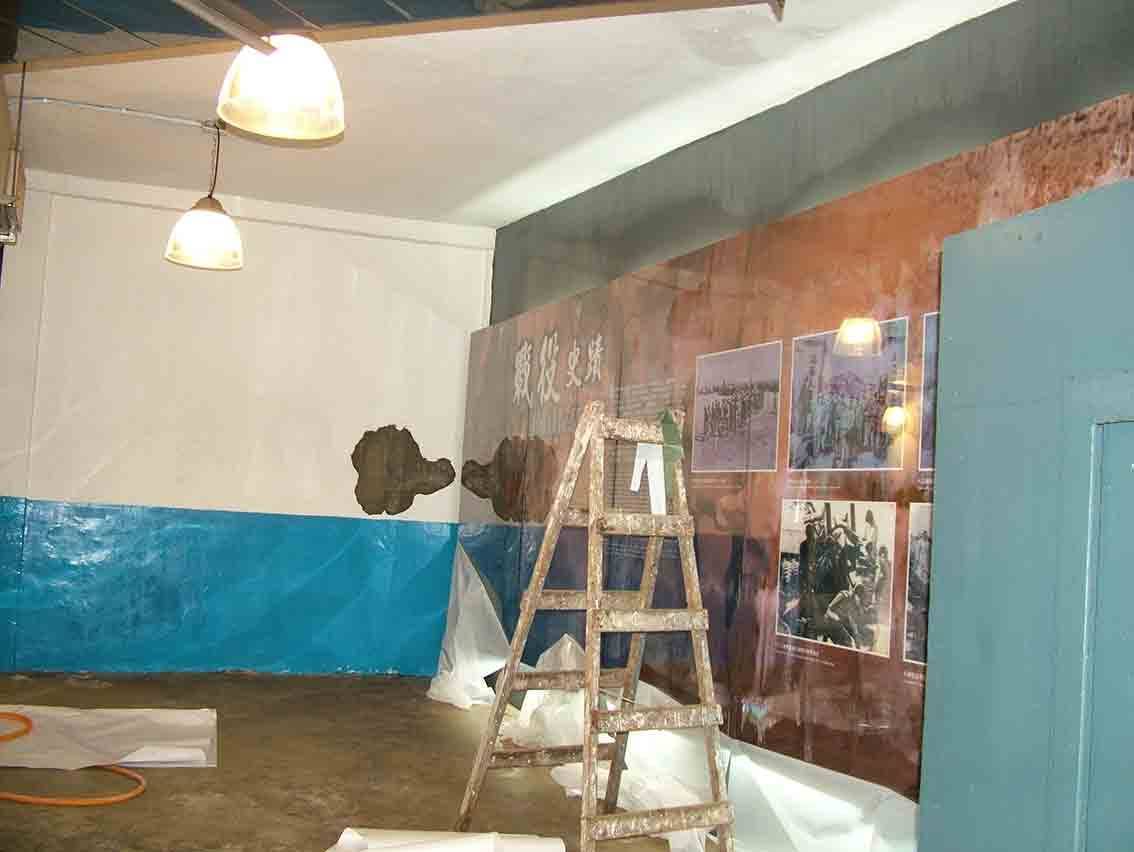 金門廣播電台展示館「戰役史蹟」展牆施工現場，鏽色大圖輸出與藍色基底牆面