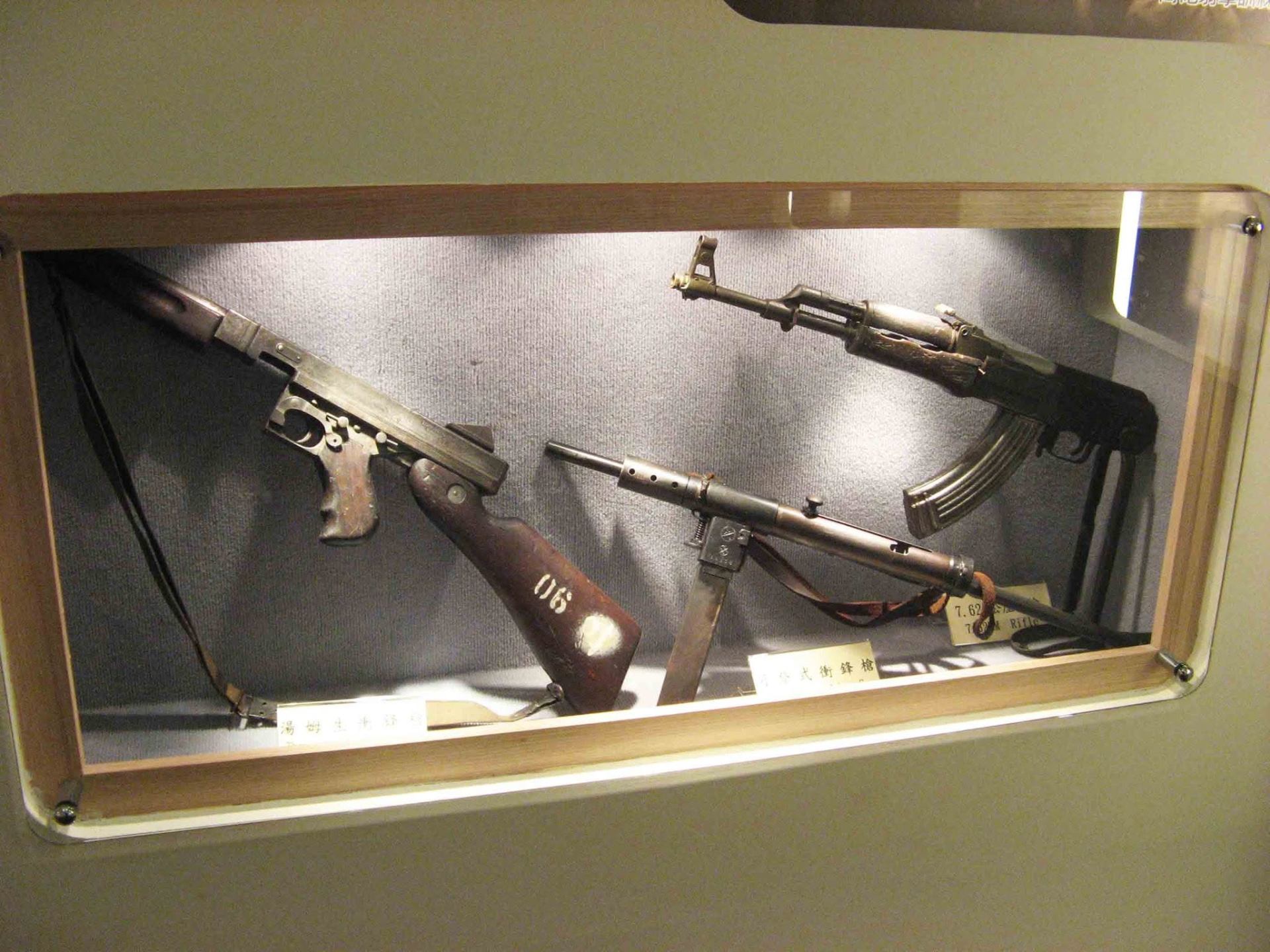 湖井頭戰史館木框玻璃櫃內展示湯姆生衝鋒槍、五○式衝鋒槍與7.62公厘步槍等繳獲輕兵器特寫