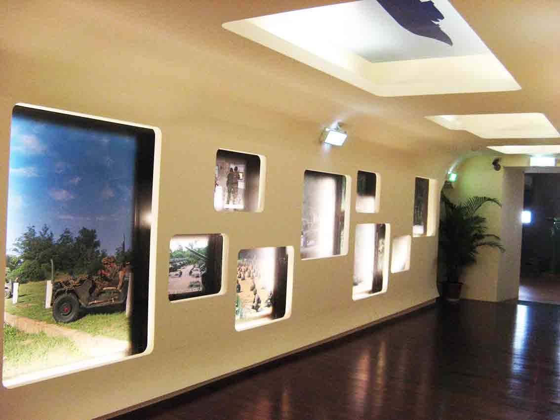 湖井頭戰史館弧形長廊展牆，圓角窗格嵌入吉普車、部隊集結與裝甲車叢林行軍等大型影像