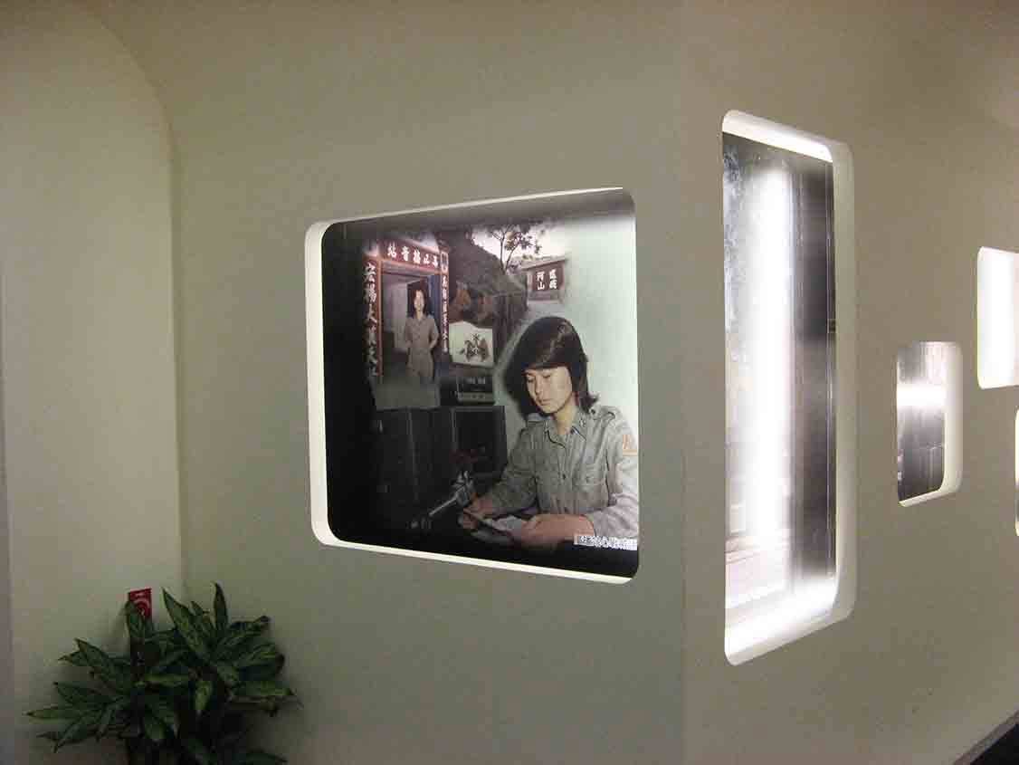 湖井頭戰史館圓拱坑道造型轉角，圓角燈箱展示女性政戰人員伏案工作與「宏揚大漢天聲」、「鞏固復興山河」標語場景