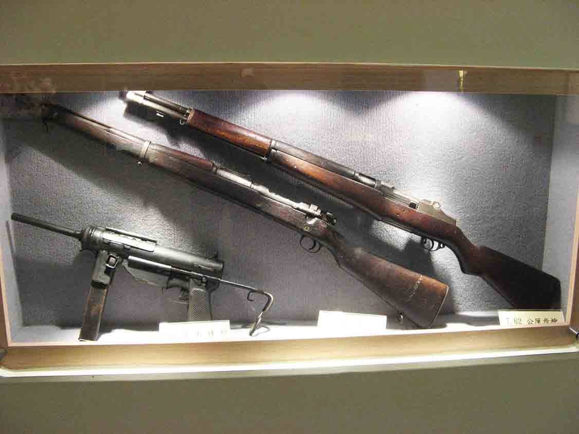 湖井頭戰史館木框玻璃展示櫃內並列陳列「7.62公厘步槍」M1 步槍與下方衝鋒槍實體特寫