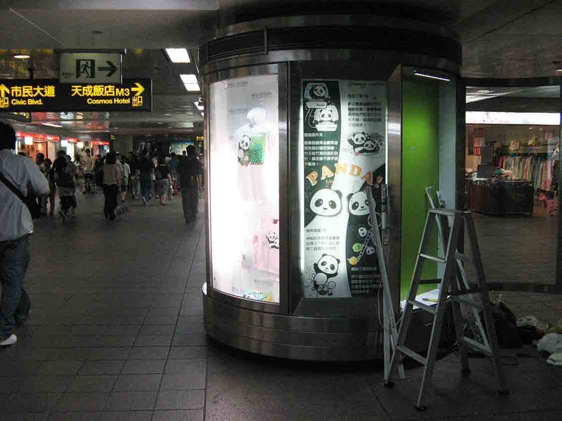 地下街熊貓主題展示亭外觀，旅客往來人潮中的櫥窗景象