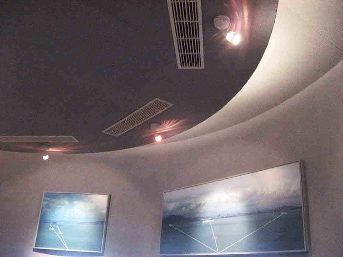 烈嶼鄉史館弧形展區仰視，深色弧形天花與淺色曲面牆面交接，下方掛載對岸海景大圖