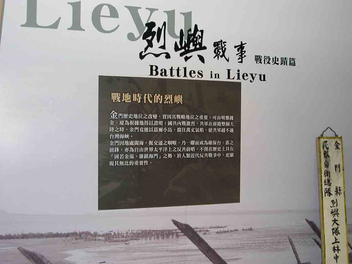 烈嶼鄉史館「烈嶼戰事 Battles in Lieyu」戰役史蹟篇標題牆特寫，灘岸軌條砦背景搭配「戰地時代的烈嶼」黑色文版