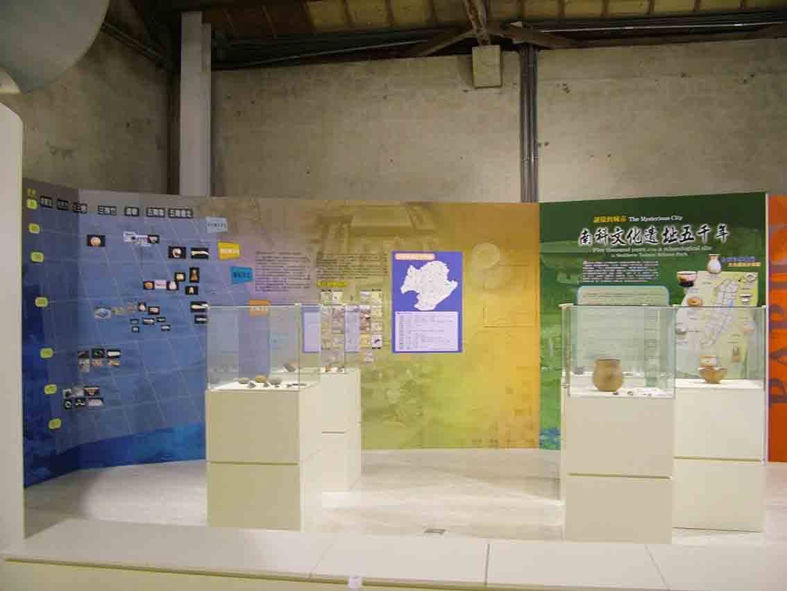 謎樣的城市主題展區，藍黃漸層背板與玻璃櫃內陶器陳列