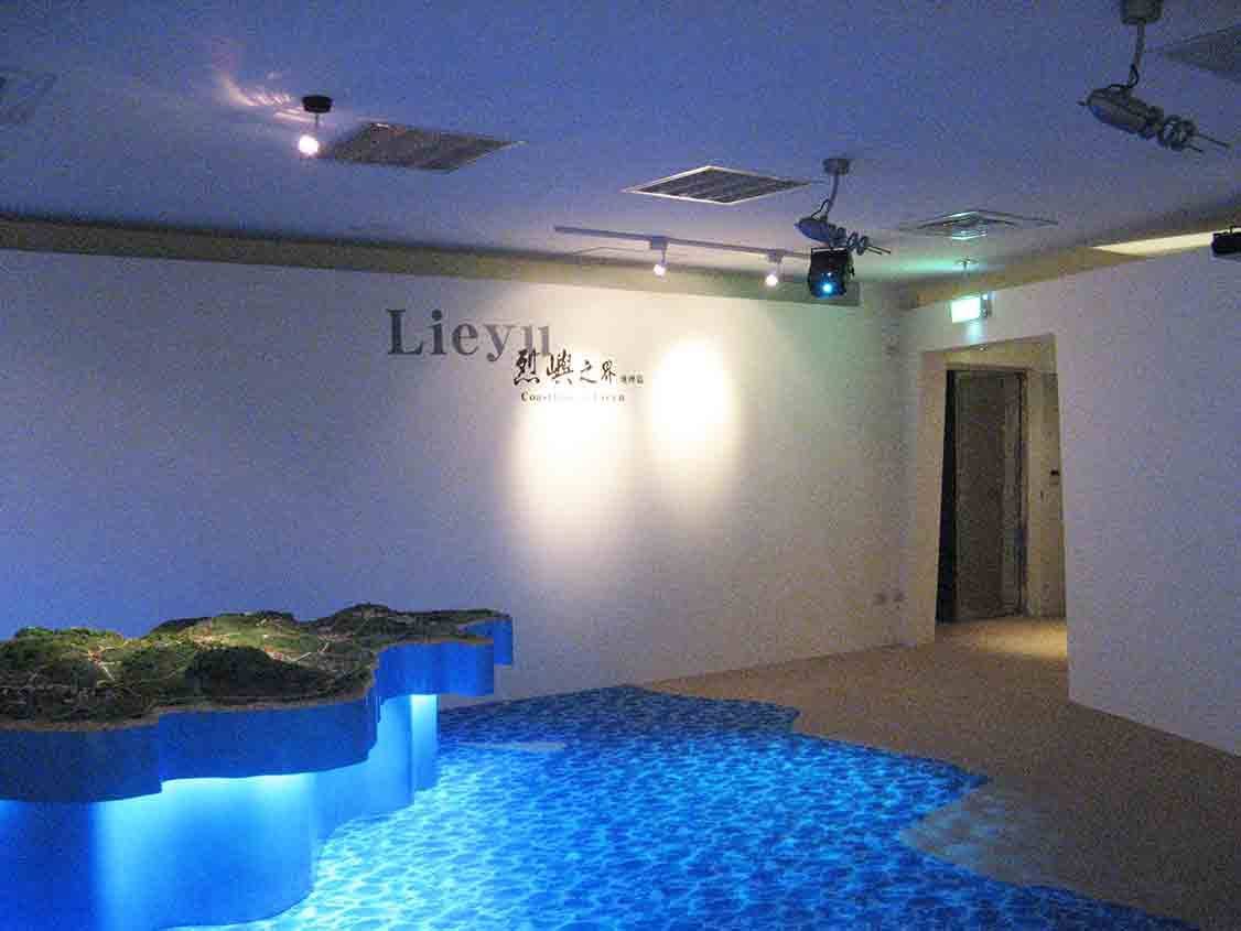 烈嶼鄉史館「烈嶼之界 Coastline of Lieyu」地理篇展區，藍光燈帶照亮立體海岸地形模型與標題牆