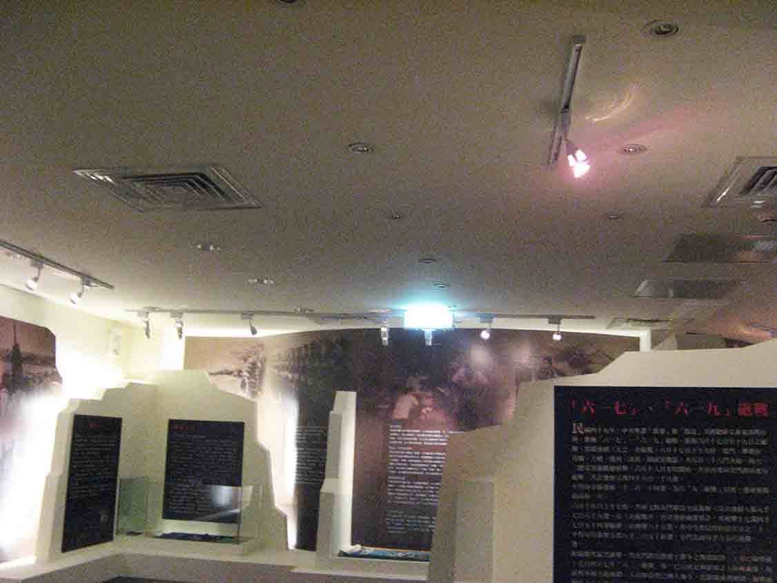 烈嶼鄉史館「六一七、六一九砲戰」展區，弧形天花軌道燈打亮黑色長文展板與碉堡造型隔板