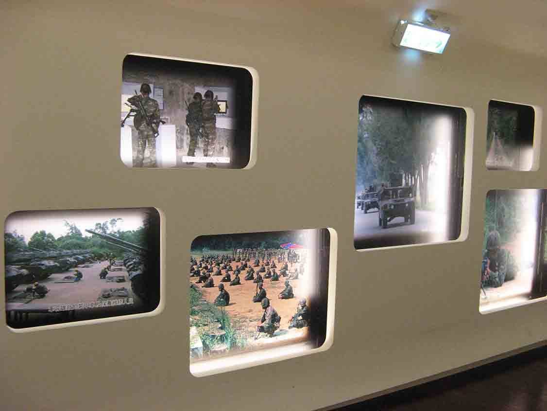 湖井頭戰史館圓角窗格展示牆，嵌入國軍持槍訓練、砲兵陣列、跪坐部隊集合與裝甲車叢林行軍等歷史照片