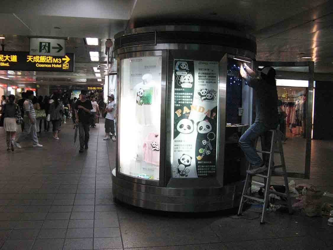 地下街展示亭施工現場，師傅站立梯上進行燈光調整